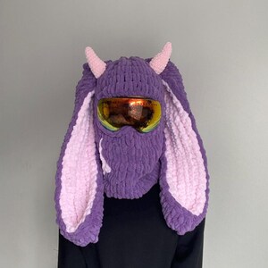 Puede incluir: Sombrero de conejo de punto morado y rosa con m&aacute;scara de esqu&iacute; y cuernos. El sombrero tiene orejas largas y esponjosas.