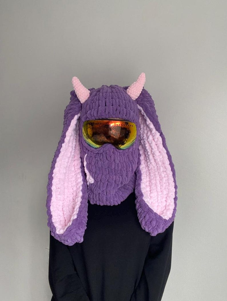 Puede incluir: Sombrero de conejo de punto morado y rosa con m&aacute;scara de esqu&iacute; y cuernos. El sombrero tiene orejas largas y esponjosas.