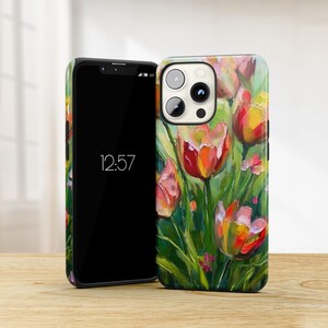 May include: A phone case with a colorful painting of tulips on a green background. The case has a black border and a cutout for the camera lens.