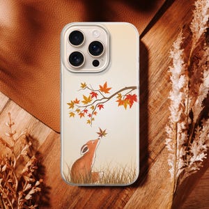 Op de afbeelding: Telefoonhoesje met een illustratie van een vos en herfstbladeren. Het ontwerp toont een vos die naar een vallend blad reikt, met een tak met rode en gele bladeren erboven. De hoes heeft een heldere afwerking.