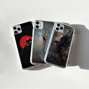 May include: Three different phone cases featuring crow designs. One case depicts a red sun and a crow, another shows a crow in a dark forest, and the final case has a crow with fire and smoke.