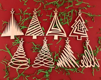 May include: A collection of eight wooden Christmas tree ornaments in various designs, including geometric and spiral patterns. Each ornament has a star at the top and is displayed on a red background with green shredded paper.