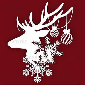 May include: White laser-cut design of a reindeer head with antlers, snowflakes, and hanging ornaments on a deep red background. The reindeer's head is in profile, with intricate snowflake details below. Two ornaments hang from the antlers.