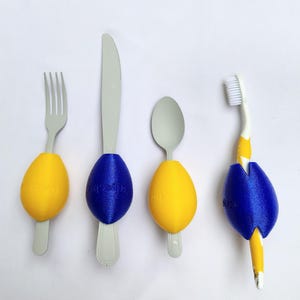 May include: Four utensils with yellow and blue 3D printed grips. A fork, knife, spoon, and toothbrush.