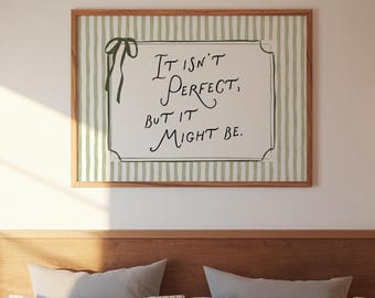 May include: A framed print with the text "It isn't perfect, but it might be." The print has a green and white striped background and a wooden frame. A green ribbon is tied to the upper left corner of the frame. The print is hanging above a bed.