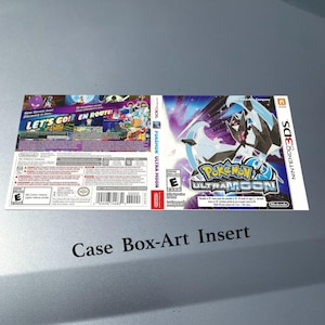 Può includere: Inserto per custodia di gioco per Nintendo 3DS per Pokémon Ultra Moon. La copertina presenta un'immagine stilizzata di una creatura bianca e nera con uno sfondo blu e viola. Il retro dell'inserto presenta grafica colorata e testo, tra cui "LET'S GO! EN ROUTE!"
