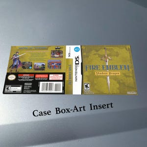 Peut inclure: Insert de boîtier de jeu Nintendo DS Fire Emblem: Shadow Dragon. La couverture présente une épée dorée et le titre du jeu en bleu. Le dos montre une illustration de personnage et des détails du jeu. Le texte "Case Box-Art Insert" est en bas.