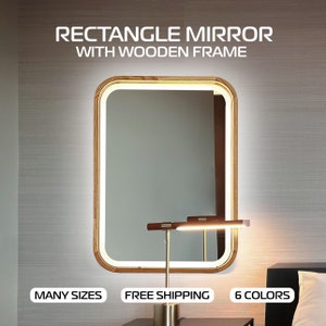 May include: A rectangular mirror with a wooden frame and a white LED light around the perimeter. The mirror is hanging on a wall and there is a table lamp in front of it.