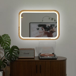 May include: A wooden framed vanity mirror with a white light around the edge, a record player with a turntable and a brown wooden cabinet with a record player on top.