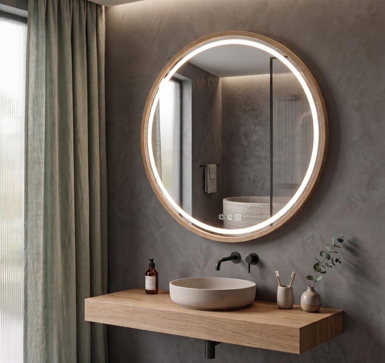 May include: A round wall-mounted mirror with a light wood frame and an integrated circular LED light strip. The mirror features a digital display at the bottom showing the time 10:10. The design includes a minimalist aesthetic with clean lines.
