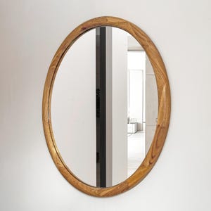 May include: A round mirror with a natural wood frame. The frame has a slightly irregular shape, giving it a rustic look.