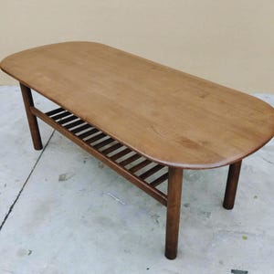 Wooden coffee table with refined top and slatted lower shelf for storage.