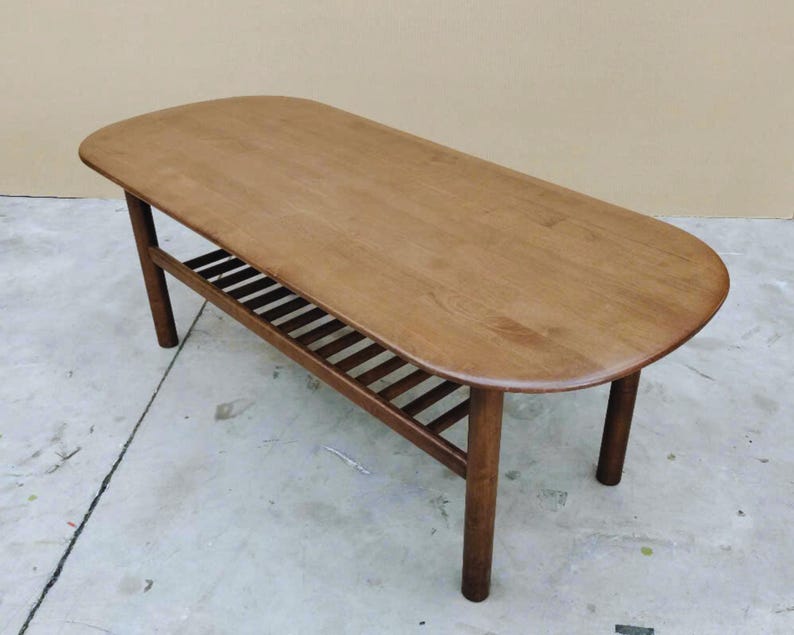 Wooden coffee table with refined top and slatted lower shelf for storage.
