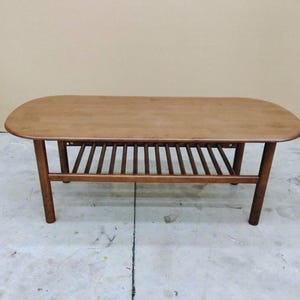 Solid Wood coffee table with round edge top in rectangle shape and slatted lower shelf for storage.