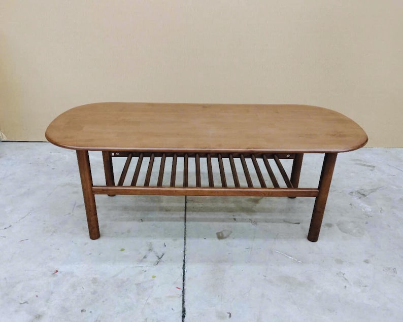 Solid Wood coffee table with round edge top in rectangle shape and slatted lower shelf for storage.