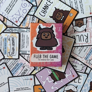Puede incluir: Una caja del juego de beber para adultos Fleb the Game. La caja es rosa y naranja con una ilustración de dibujos animados de una criatura marrón con una nariz rosa y cuernos. El texto en la caja dice "Fleb the Game, The Drinking Party Game".