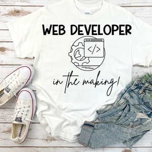 Puede incluir: Camiseta blanca con texto negro que dice "WEB DEVELOPER in the making!" y un gráfico de una pantalla de computadora con código dentro de un engranaje.