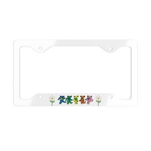 Peut inclure: Cadre de plaque d'immatriculation en plastique blanc avec une rangée d'ours dansants colorés et des fleurs blanches en bas.