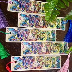 May include: Five colourful bookmarks featuring a detailed illustration of a snake with a yellow, blue and green pattern. Each bookmark has a tassel attached.