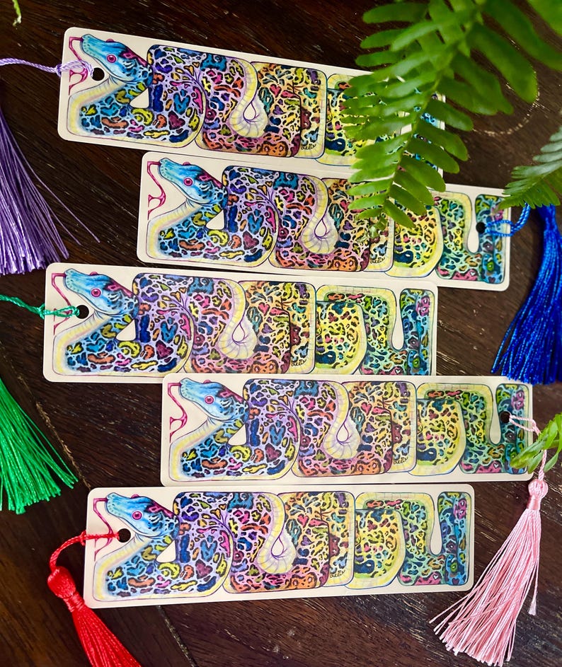 May include: Five colourful bookmarks featuring a detailed illustration of a snake with a yellow, blue and green pattern. Each bookmark has a tassel attached.