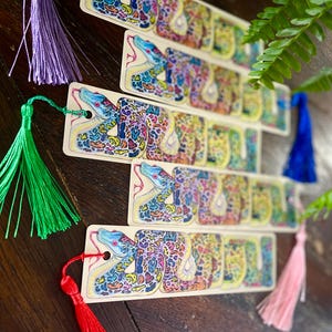 May include: Set of five colourful bookmarks featuring a detailed illustration of a snake with a patterned skin. Each bookmark has a tassel attached.