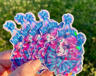 May include: A set of five iridescent holographic stickers featuring a cartoon illustration of a sad clown with pink hair wearing a blue and pink party hat. The clown has a blue bow tie and is crying a single tear.