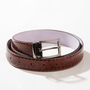 以下が含まれることがあります： 銀色のバックルが付いた茶色の革ベルト。ベルトはヘビ柄でリバーシブルです。