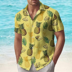 Könnte beinhalten: Ein gelbes, kurzärmeliges Hemd mit Knöpfen und einem Ananasdruck.