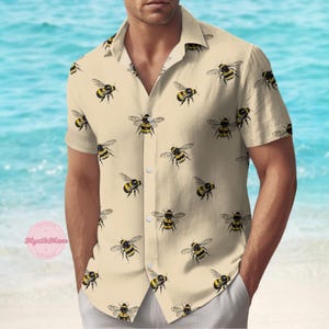 Può includere: Una camicia beige a maniche corte con bottoni e un motivo ripetitivo di api gialle e nere.