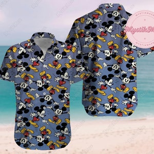 Puede incluir: Una camisa azul de manga corta con botones y un patrón repetido de Mickey Mouse en varias poses. La camisa tiene un cuello blanco y un cierre de botones.