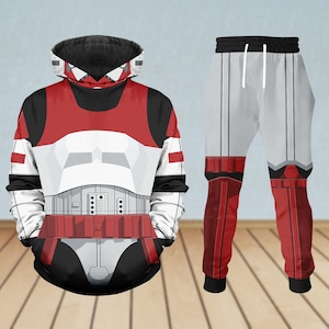 May include: A matching two-piece set consisting of a long-sleeve hooded sweatshirt and sweatpants. The garments feature a graphic print mimicking white, red, and black armor plating with geometric panels, utility belt details, and white drawstrings.