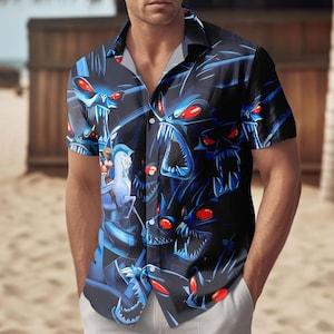 May include: Short-sleeved button-down shirt featuring a dark blue design with cartoon monsters with red eyes and sharp teeth. The shirt has a classic collar and is worn by a person.