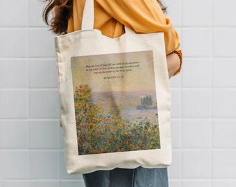 Könnte beinhalten: Eine weiße Canvas-Tragetasche mit einer Blumenlandschaft und einem Zitat aus Römer 15,13. Das Zitat lautet: "Der Gott der Hoffnung erfülle euch mit aller Freude und allem Frieden im Glauben, damit ihr überströmt von Hoffnung seid durch die Kraft des Heiligen Geistes."