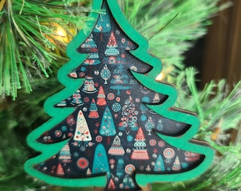 May include: A wooden Christmas tree ornament with a green outline and a dark background filled with colorful Christmas tree designs. The ornament is hanging on a green Christmas tree.