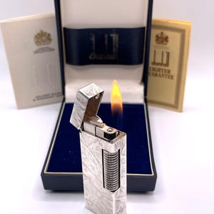 Encendedor vintage Dunhill Rollagas en funcionamiento con el logotipo “d” en muaré plateado, c. 1980, con caja y papeles
