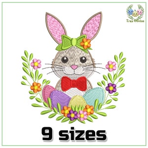 Puede incluir: Diseño bordado de un lindo conejito con un lazo verde y una pajarita roja, rodeado de huevos de Pascua coloridos y hojas verdes con flores rosas, amarillas y moradas. El diseño está disponible en 9 tamaños.