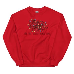 May include: Red sweatshirt with the text "I'M FINE. EVERYTHING'S FINE." and a graphic of tangled black lines with colorful dots. The sweatshirt is made of a soft material.