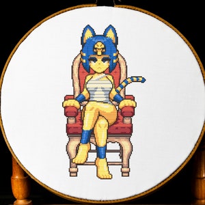 May include: Cross-stitch embroidery of a cartoon character seated on a red throne. The character has yellow skin, blue hair, and is wearing a white and blue outfit. The embroidery is framed in a wooden hoop.