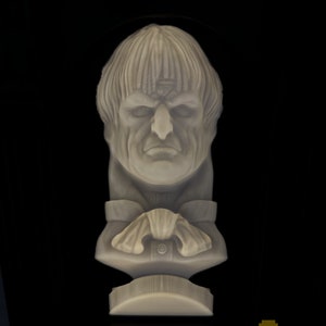 May include: A 3D printed bust of a person with a short, wavy hairstyle. The bust is made of a light gray material and is mounted on a small base.