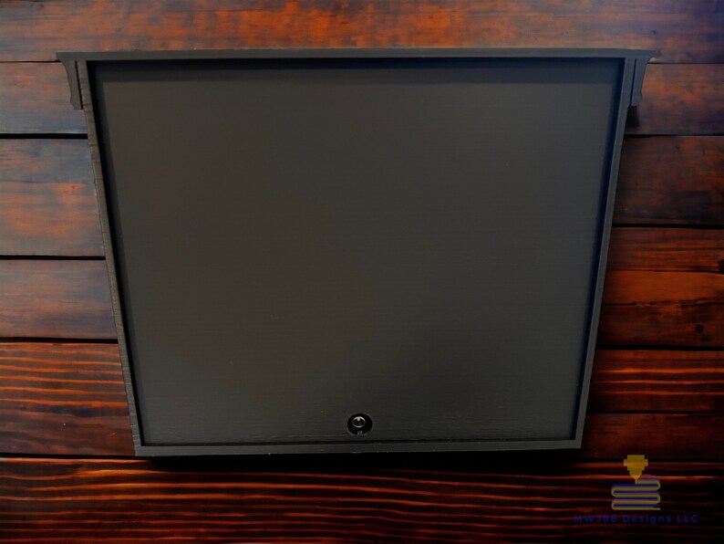 May include: A dark brown, rectangular mailbox with a single keyhole on the front. The mailbox is mounted on a wooden wall.