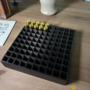 May include: A black, square, 3D-printed tray with numerous individual compartments. A selection of gold-colored objects are placed in some of the compartments. The tray is on a wooden surface. The text "MWJ88 Designs LLC" is visible.