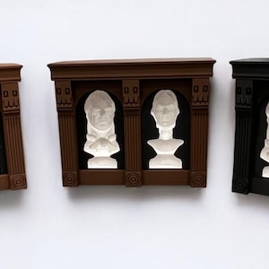 May include: Three decorative wall plaques with a brown, black, and white finish. Each plaque features two white busts in a recessed alcove with a decorative frame.