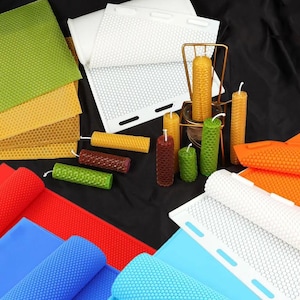 May include: A collection of colorful beeswax sheets and honeycomb-patterned candles in various sizes and colors, including green, yellow, and brown. Rolled sheets of red and blue are also visible, along with white honeycomb sheets.
