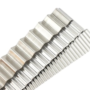 Puede incluir: Un juego de tres herramientas de decoración de pasteles de metal de color plateado con un borde ondulado y festoneado. Las herramientas están apiladas una encima de la otra.