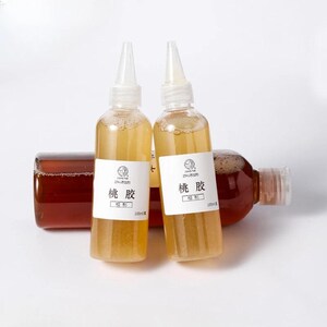 May include: Two clear plastic bottles with white labels and a yellow liquid inside, standing upright. The bottles have white pointed caps. A third bottle, filled with a darker liquid, lies horizontally behind them. The labels have Chinese characters.
