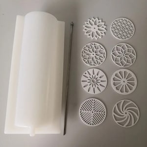Pu&ograve; includere: Uno stampo per candele cilindrico bianco con un'asta di metallo e otto sottobicchieri circolari bianchi dal design intricato. I sottobicchieri presentano vari motivi geometrici e floreali, perfetti per l'arredamento della casa o progetti di artigianato.