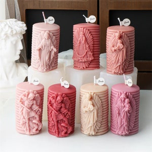 May include: Eight pink and red pillar candles with religious figures in relief. The candles are decorated with a striped pattern and have a white label with the word "Smile" on them.