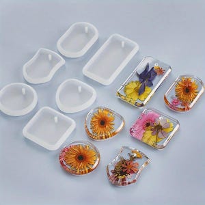 Può includere: Una collezione di stampi in resina trasparente di varie forme, tra cui cerchi, quadrati e rettangoli, insieme a pendenti in resina finiti con fiori secchi nei toni del giallo, arancione, rosa e viola. Ogni stampo ha un piccolo foro per appendere.