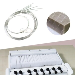 May include: White musical instrument with black keys and a set of silver strings. The instrument has a white frame and a set of white plastic reeds. The strings are coiled and come with a metal ring.