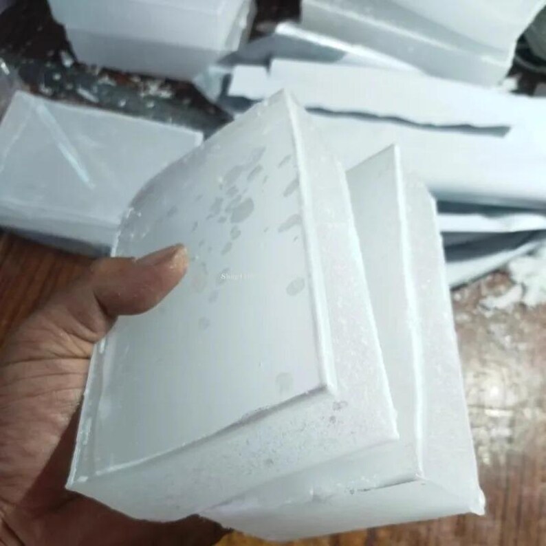 Może przedstawiać: Prostokątny blok z litego białego wosku o gładkiej, płaskiej powierzchni i lekko teksturowanych, nieprzezroczystych krawędziach. Materiał wydaje się gęsty i jednolity kolorystycznie, z subtelnymi r&oacute;żnicami w wykończeniu powierzchni.